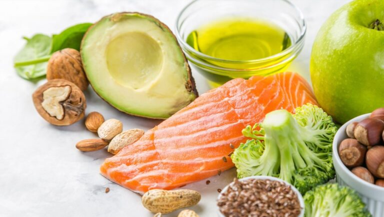 Image of various foods, such as avocado, salmon, broccoli, and nuts.
