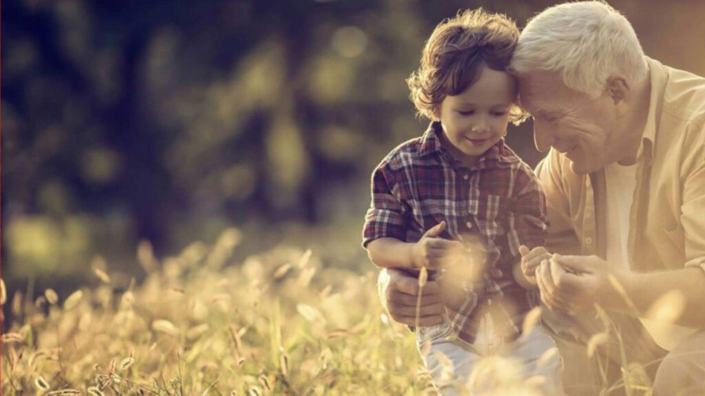 Image of elderly man and child in field.