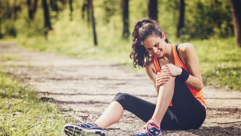 Image of runner on ground in pain, holding left knee.